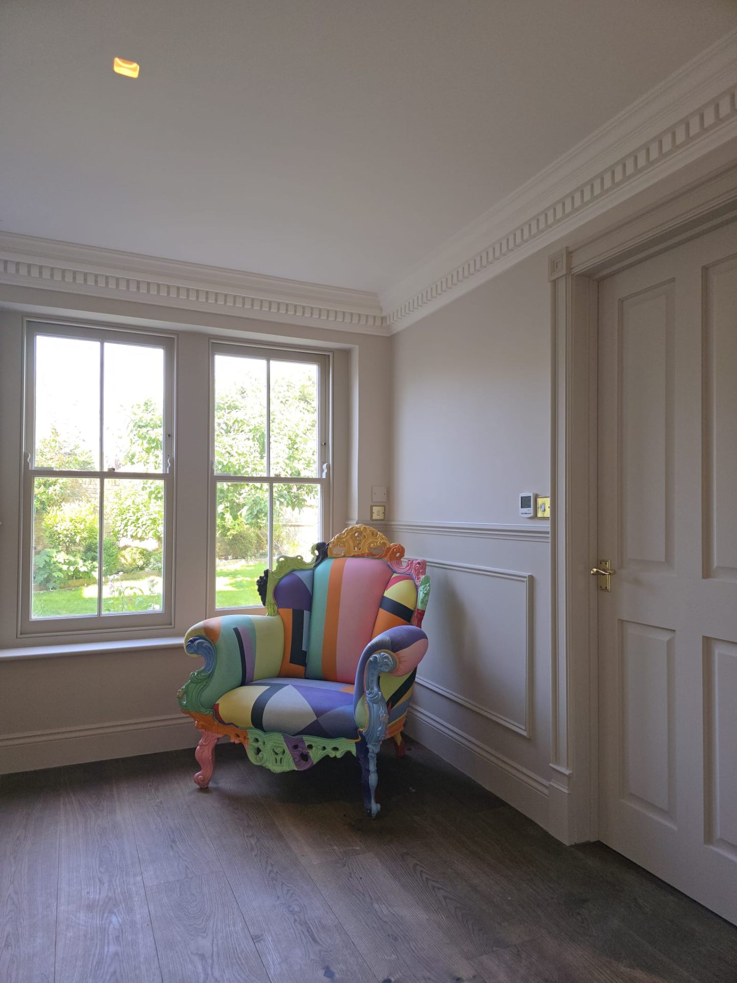 Period room with colourful statement furniture and decorative wall panelling