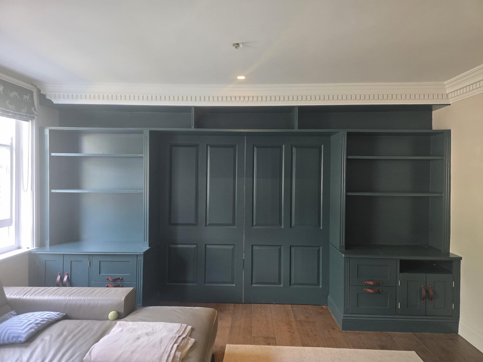 Bespoke teal feature wall cabinetry with decorative panelling by Shreeve and Sons