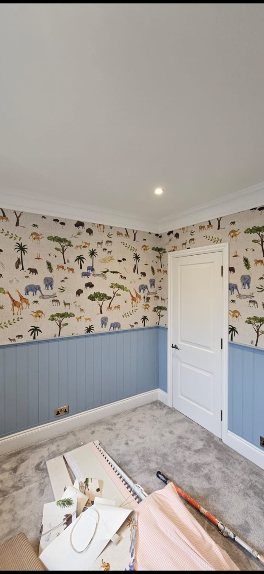 Children's bedroom with safari animal wallpaper above blue painted tongue-and-groove panelling
